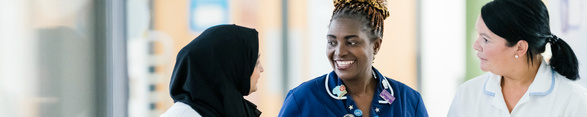 diverse trio of female nursing staff chatting and smiling in a hospital setting 