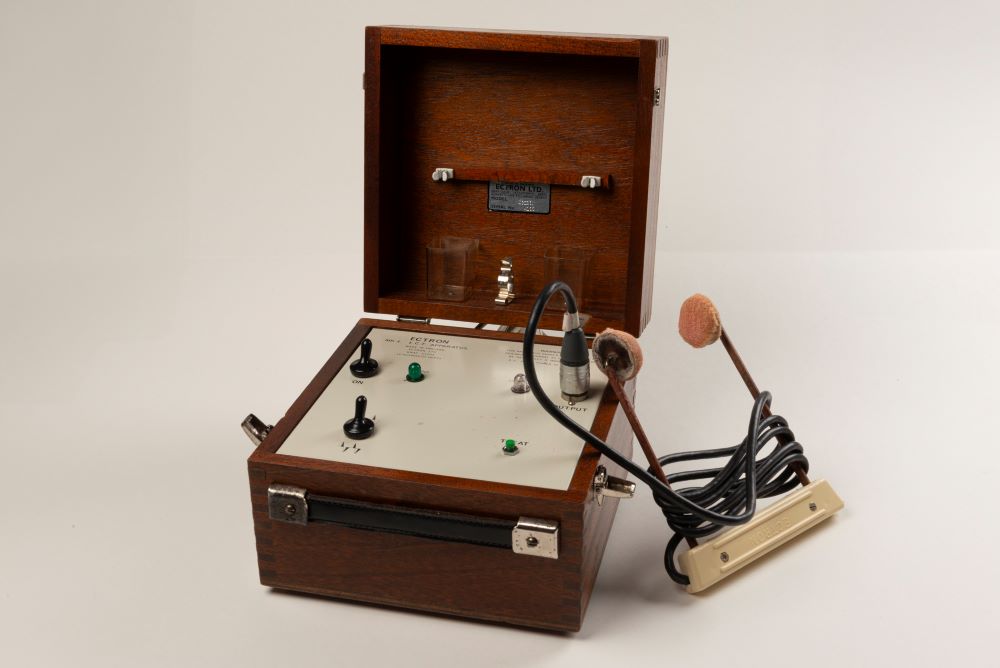 Electroconvulsive Therapy (ECT) Machine from the 1960s. The machine is in a wooden box with a leather handle, and the interior is cream with dials and switches. 