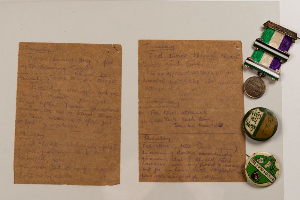 Two pages from Elsie Duval's diary. The writing is very faint, but days of the week are visible with short entries. Along the side are badges and medals.