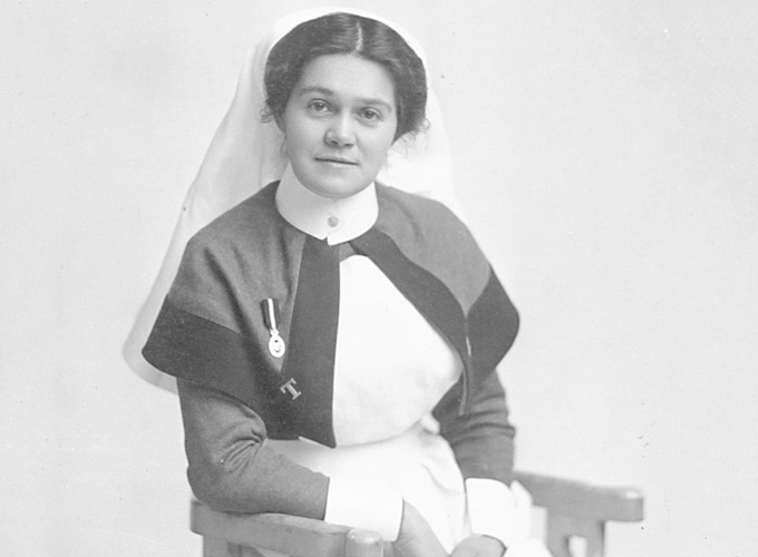 Black and white photograph of a VAD from the waist up in uniform with a medal on on her cape.