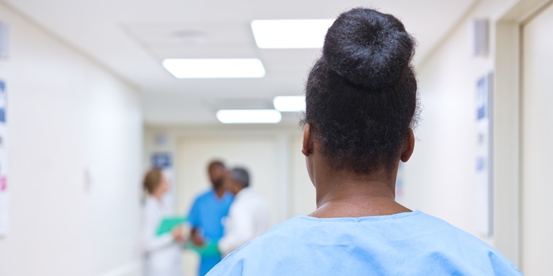 back of nurse's head in hospital corridor, blurred background with other medical staff talking