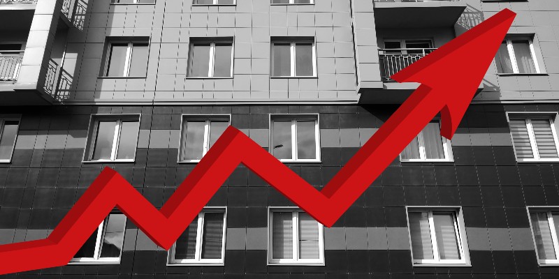 A photo of housing with a red upwards arrow to illustrate a London region news article responding to a housing consultation by the Mayor of London