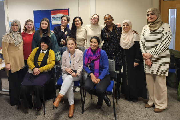 A group of 12 refugee nurses stood in a group and smiling at the camera