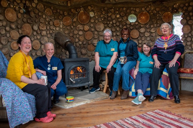 Kiera and hospice volunteers sat by a woodburner in the roundhouse