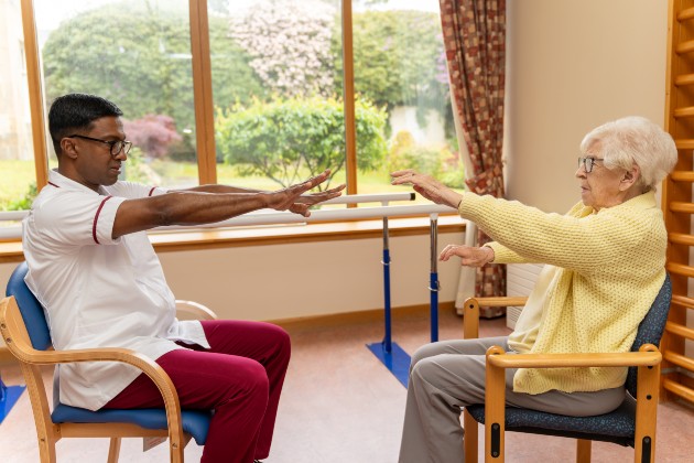 Nursing support worker doing arm stretching exercise with an older woman