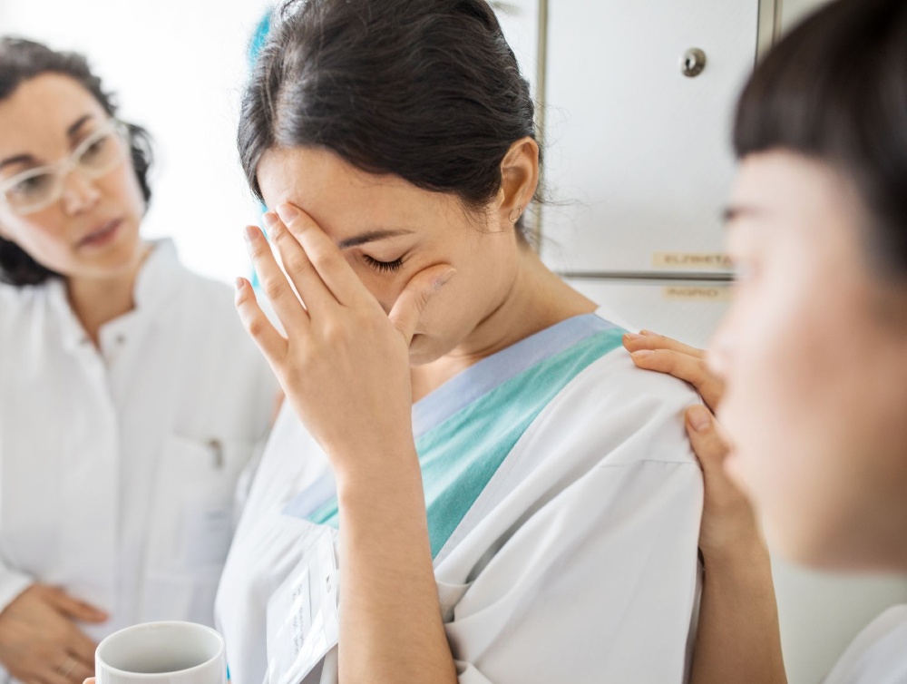 Woman looks upset and is comforted by her colleagues