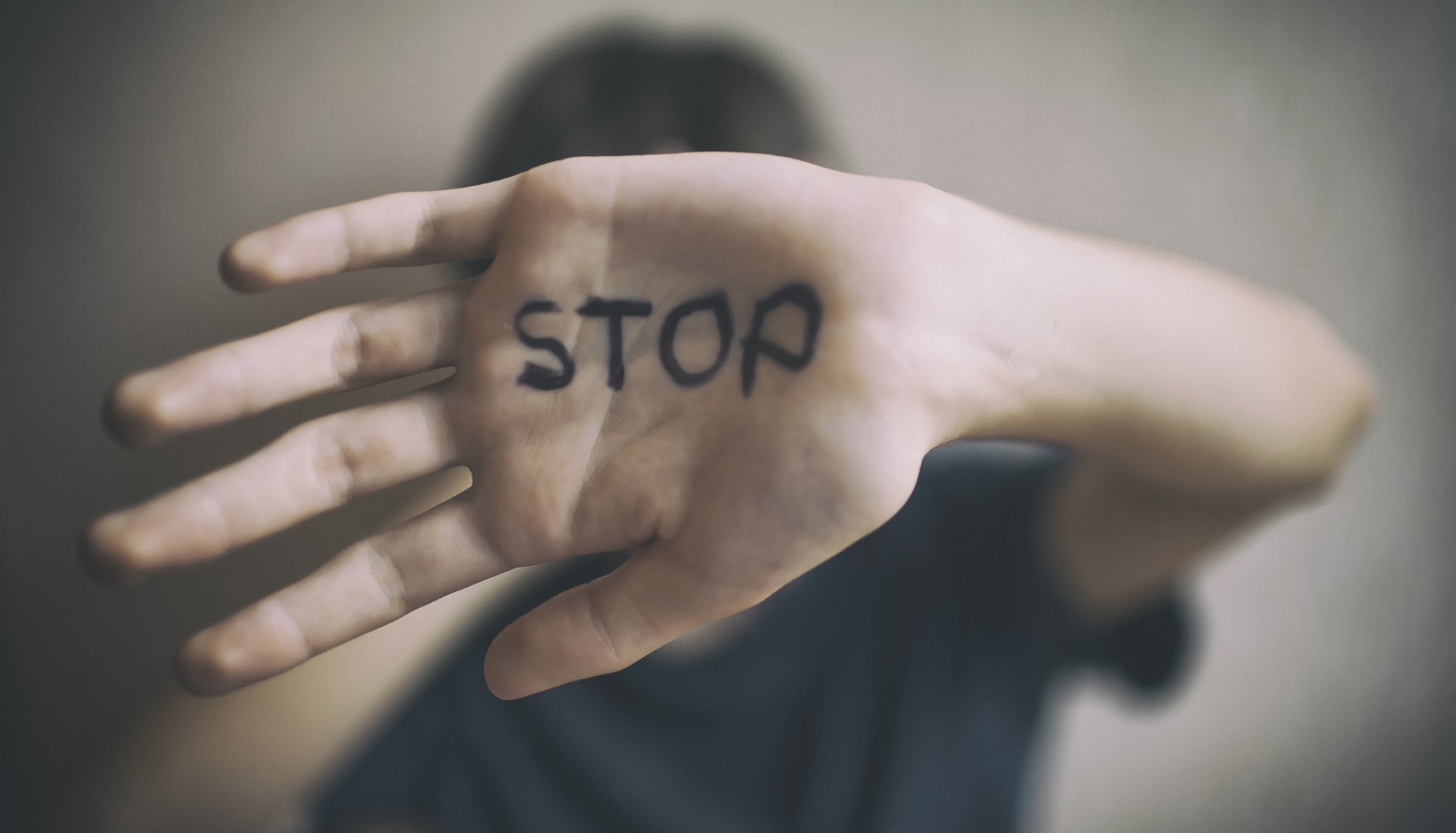 woman with hand to camera with stop written in pen on it