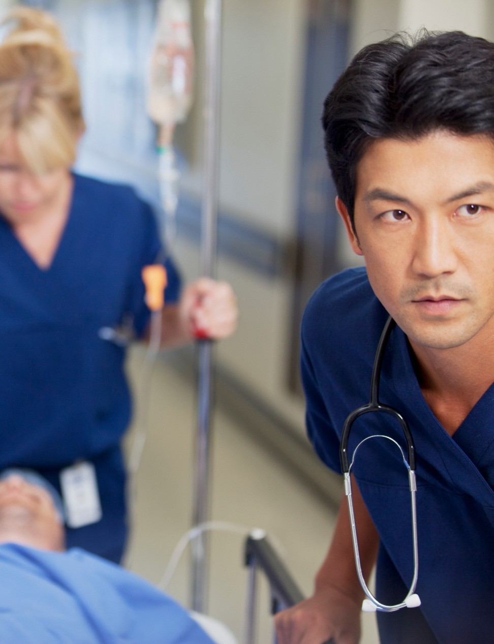 Nursing staff push a patient in a hospital bed