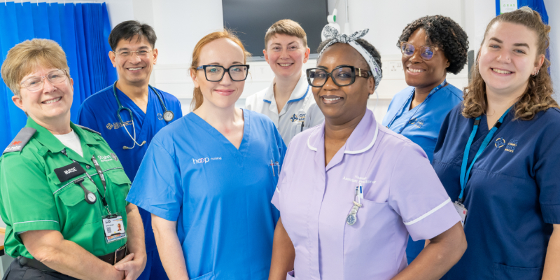 Group of healthcare staff in uniforms standing together in a hospital ward.