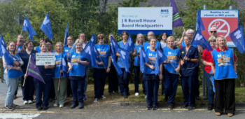 Picture of nurses lined up at an event holding placards and flags